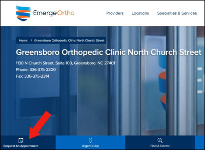 A young woman is sitting on the ground holding a laptop computer, looking at the camera and smiling.